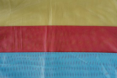 Breathable and quick-drying polyester mesh fabric for bags. Elastic mesh. Three colors blue, red, and khaki. Folded fabric. Copy space. clipart