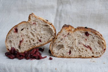 Kenevir masa örtüsünün üzerinde ikiye bölünmüş bir somun ekmek. Kurutulmuş yaban mersinli ekmekler. Kırsal yaşam.
