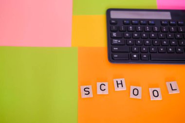 The word School. Keyboard on a colorful background. School educational electronic gadgets. Modern school concept. Copy space. clipart