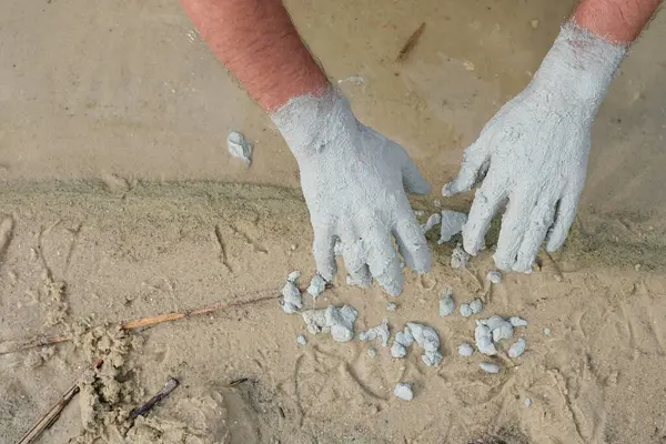 stock image Unique blue clay from the bottom of Lake Svityaz, Volyn, Ukraine. Mud baths with blue clay. A layer of clay is applied to the man's hands. Sandy Lake shore background.