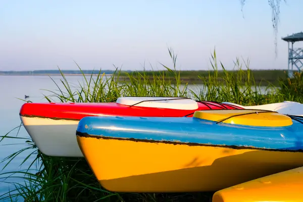 stock image Colorful of kayaks noses or canoes in the morning on a lake background. Entertaining water transport. Active recreation rental of watercraft.