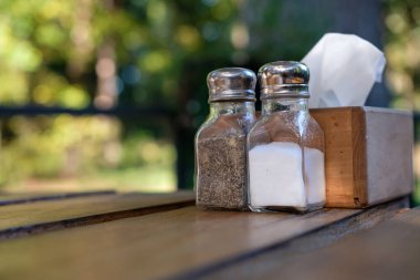 Table setting in the rustic forest restaurant. Condiments and napkins are on the pallet wood table. Scene on the terrace before eating in the evening golden hour. Shallow depth of field. Copy space. clipart