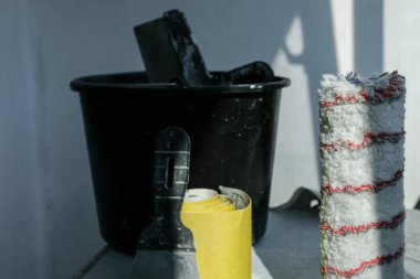 Boya silindiri odaklı. Tamir edilmiş duvar arkaplanının boyama işleri için kullanılan araçlar. Güneş gölgeleri. Tamir edilecek bir takım eşyalar. Gerçek hayat. Boşluğu kopyala.