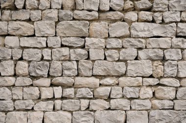 Taş duvar pürüzlü, pürüzlü gri taşlarla örülmüş. Güney Fransa 'dan geleneksel taş ustalığının ayrıntıları.