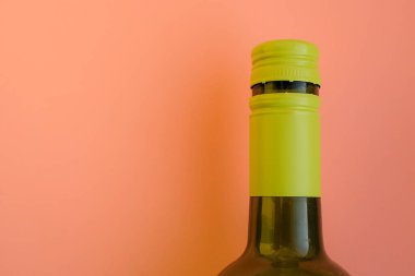 Yumuşak şeftali rengi arka planda yeşil vida kapaklı yeşil cam şişe. Minimalizm. Şarap ve ambalaj tasarımı. Boşluğu kopyala.