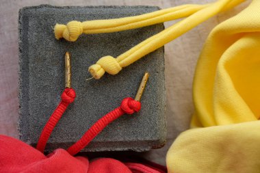 Details hoodie drawstrings. Vibrant red drawstrings have gold-colored metal aglets. Soft yellow ends that are knotted. clipart