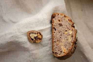 Kırık ceviz ve kenevir masa örtüsünde ekşi ekmek. Ceviz, kuru üzüm ekmeği. Boşluğu kopyala.
