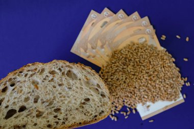 Mavi bayraklı ekmek, buğday taneleri ve Avrupa Birliği para birimi. Üst Manzara. Ekmek odağı. Sığ alan derinliği.