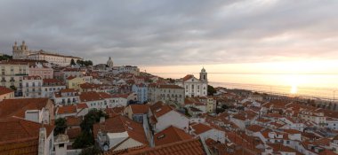 A panorama image of the famous 'Miradouro de Santa Luzia' during sunrise over the bay. In the image is the Monestary of Sao Vicente de Fora, the National Pantheon Church and the church of Santo Estevao.