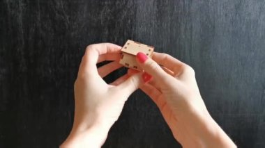 İki kadın eli, siyah arka planda ahşap bir ev gösteriyor. Konut, ev ve daire seçimi kavramı.