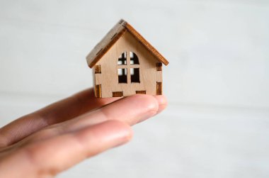One small wooden house on a man hand on a white background, the concept of family happiness, buying a house