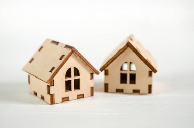 Two small wooden houses on a white wooden background, the concept of family happiness, buying a house
