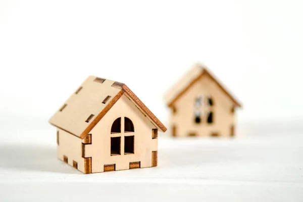 Two small wooden houses on a white wooden background, the concept of family happiness, buying a house