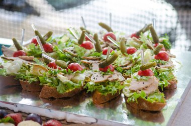 Akşam yemekleri, küçük tavuklar ve salatalıklı sandviçler güneş ışığında tabakta.