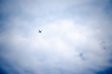 Gökyüzünde uçan yolcu uçağı, beyaz bulutlu mavi gökyüzü.