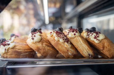 Kafedeki buzdolabının vitrininin arkasında kremalı ve dutlu puf böreği.
