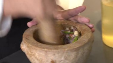 Şef kahverengi taştan havan topuna baharatlı karides ezmesi atıyor..