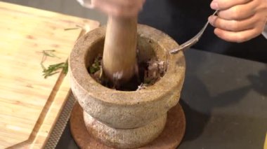 Şef kahverengi taştan havan topuna baharatlı karides ezmesi atıyor..