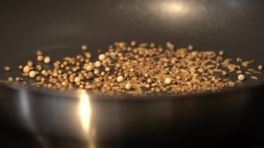Baharatlar, taneler ve bitki tohumları Asyalı şef tarafından elektrikli ocakta tavada kızartılıyor.. 