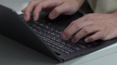 Tayland İngilizcesi klavyeli siyah bir dizüstü bilgisayarda yazan bir adam var..