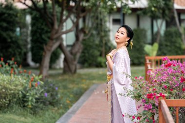 Geleneksel Tayland kostümlü bir kadın portre çekimi sırasında tahta köprüde duruyor..