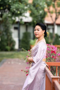 Geleneksel Tayland kostümlü bir kadın portre çekimi sırasında tahta köprüde duruyor..