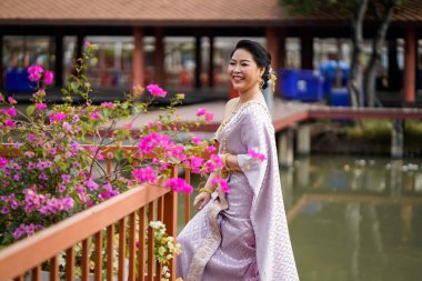 Geleneksel Tayland kostümlü bir kadın portre çekimi sırasında tahta köprüde duruyor..