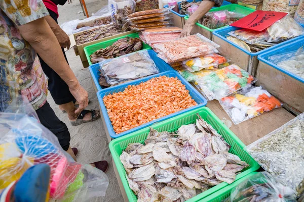 Fresh fish packed in clear bags laying on the table at the local food stall are being picked up by many customers.