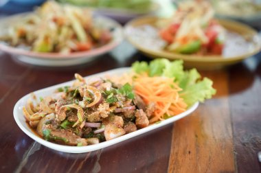 Baharatlı soslu Tayland ızgara domuz boynu. Baharatlı ızgara domuz eti salatası. Tahta masada taze sebzeyle servis ediliyor. Yemeye hazır..