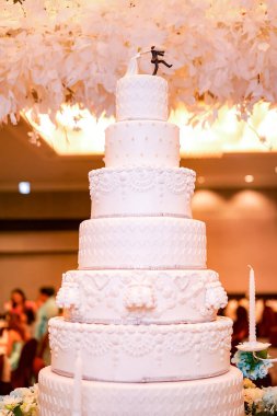 Düğün çifti pasta tepeciği, bir gelin bebeği koşan bir damadı yedi katlı beyaz düğün pastasının üstünde yakalayıp götürüyor..