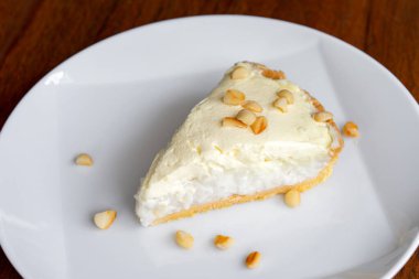 Coconut Cream Pie in the white dish on the wood table that topping with macademia. Shooting in the sunlight. clipart