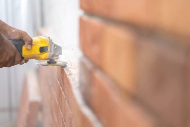 Öğütücü Makinesi 'ne yakın İşçi el ele tutuşun testere, öğütün, kontrol edin ve detaylı poliüretan tuğla duvarını tozla kaplayın..