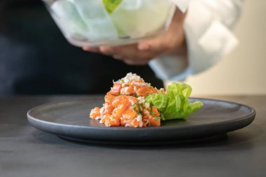 Baharatlı Çiğ Somon Salatası Tayland usulü kızarmış balık derisi ve üzerinde sarı çiçek ve tabağın etrafında mikro bitki ile süslenmiş. Hizmet etmeye ve yemeye hazır..