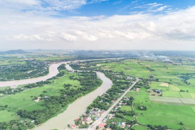 Top view of the Sakae Krang River, Uthai Thani Province where both sides of river are filled with lush green trees. There are community near waterside.