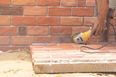 Kapalı işçi el testeresi makinesini tutuyor ve duvar kurulumu için tuğla köpük levha kesiyor.