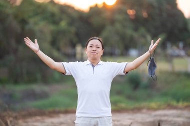 Asyalı adam maskesini çıkar ve altın alacakaranlıkta elini kaldır.