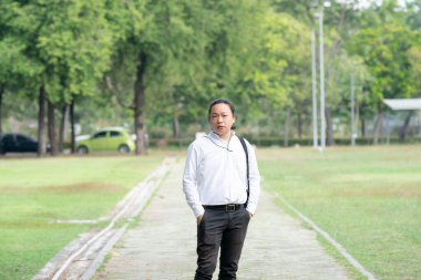 Asyalı, serbest çalışan, uzun saçlı bir adam. Bahçenin bahçesinde yürürken, yanında fotoğraf makinesi vardı..