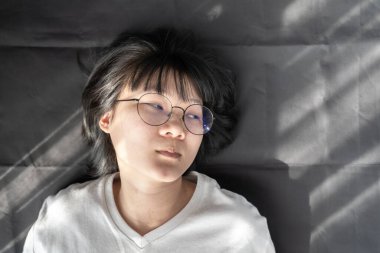 Sevimli kısa saç - gözlüklü Asyalı kadın siyah kırışık arka planda yatıyordu..