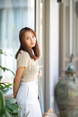 Asyalı bir kadın utangaç, güzel bir gülümseme ve mutlulukla kameraya bakar.