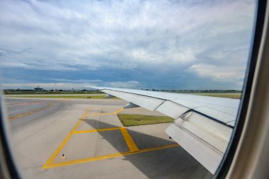 Uçak penceresinden, Suvarnabhumi Uluslararası Havalimanı 'nın yanı sıra uçağın geniş kanatları gün ortasındaki koşuşturma sırasında görüntülenir..
