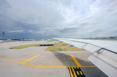 Samut Prakan, Tayland - 9 Temmuz 2023, Suvarnabhumi Uluslararası Havalimanı 'nı ve öğlen saatlerinde uçağın kanatlarını ele geçiren uçağın penceresinden İçeriden Dışarıya Bakış.