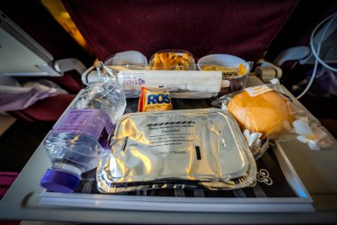 Bangkok, Thailand - 9 July 2023, A delightful in flight meal featuring a box set, water drink, desserts and others, thoughtfully arranged in front of the passenger's view at the seat. clipart