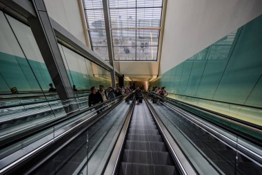 Londra, İngiltere - 10 Temmuz 2023, Heathrow Uluslararası Havalimanı 'ndaki yürüyen merdivende bulunan yolcular ait oldukları bir sonraki kata taşınıyor..