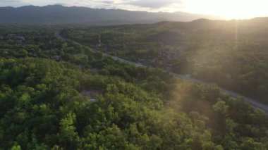 Yerleşim alanı, orman, dağ, mavi gökyüzü ve Tak vilayetindeki Drone çekiminden yüksek açılı güneş ışığına sahip yol manzarası, Tayland 'ın kuzey kırsalında..