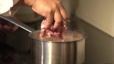 Elektrikli ocakta haşlanmış çorba stoğuyla alüminyum bir tencerede çiğ domuz eti pişirmek eti hazırlamanın güvenli ve yaygın bir yoludur..
