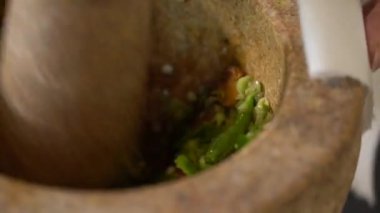 Şef ağır harç ve tokmağı alır, ham baharat ve otların karışımını ince bir öğütülmüş Tayland yeşil köri macununa dönüştürmeye hazırdır..