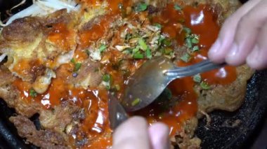 Sıcak, siyah bir tavada, fasulye filizi ile kızarmış istiridye omleti. Sıcak tavada, bu menü servis edilmeye ve tüketilmeye hazır..