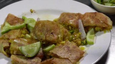 Beyaz tabakta tavuk Mataba ve yanında da bir kase sos. Tüm bu menüler paslanmaz yüzey masasında..