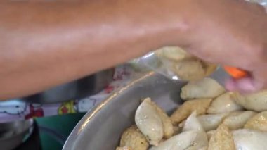 Tayland 'da kızarmış köfteler, yerel kadın satıcı büyük bir tencerede kızarmış köfte ve satış için kızgın yağ pişiriyor..