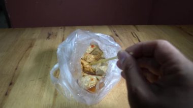 Lezzetli sosla kaplı plastik poşette kızartılmış köfteler. Tahta bir sopayla tahta bir sopayla yemeye hazır..